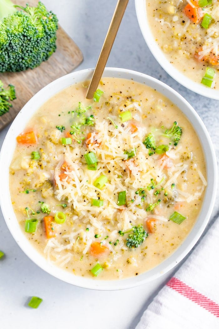 Tigela de sopa de brócolos de cheddar com uma colher de ouro na tigela.