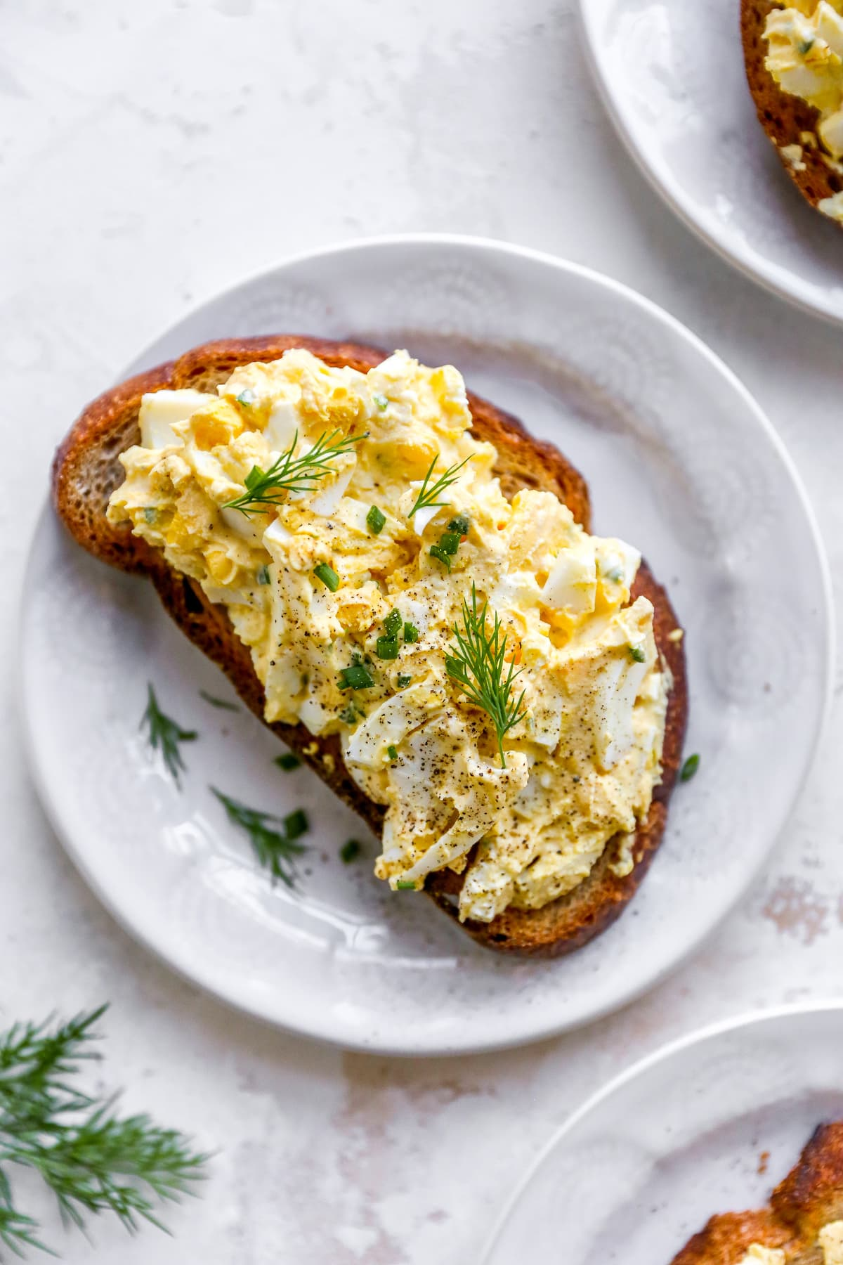 Um prato com uma fatia de pão coberto com uma salada de ovo saudável.