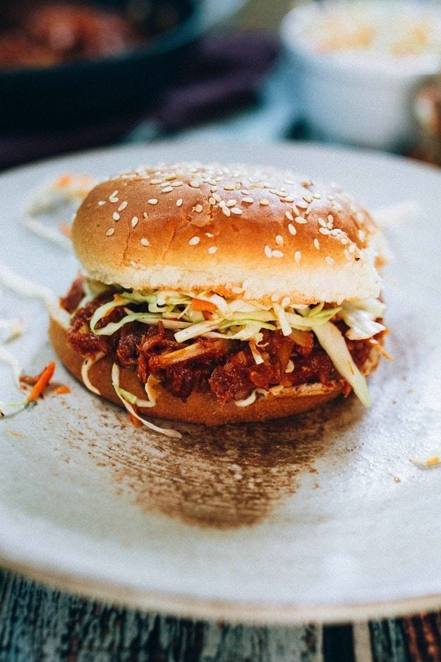 Corações de palmito bbq sanduíche com bofetada num pão de sementes de sésamo num prato branco.