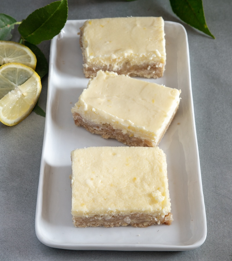 3 quadrados de cheesecake de limão em um prato branco.