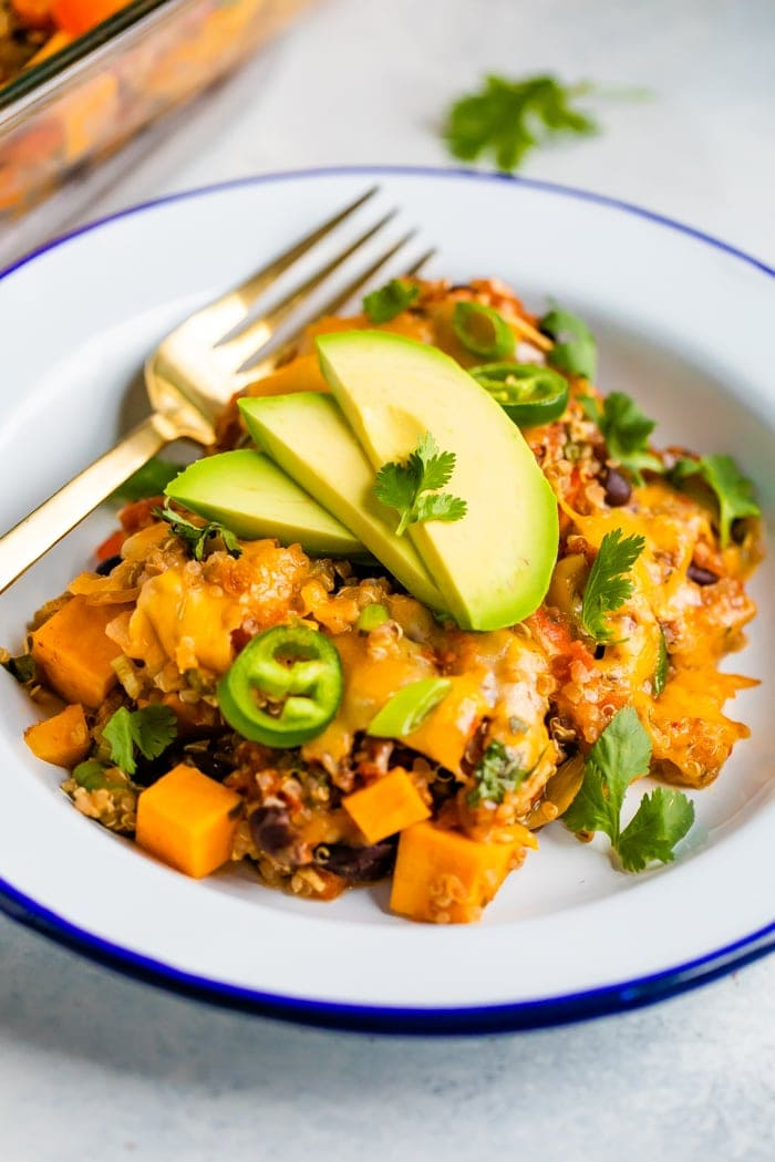 Prato com uma caçarola queijada de quinoa mexicana coberta com fatias de jalapenos, abacate e coentro.