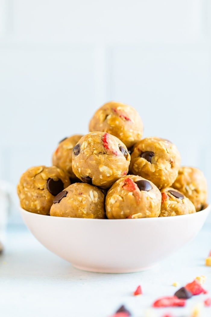 Tigela de manteiga de amendoim e picadas de proteína gelatinosa feitas com aveia, morangos secos e lascas de chocolate.