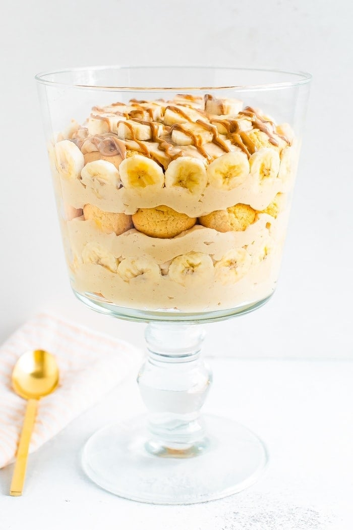 Vidro trifle com camadas de pudim de manteiga de amendoim, fatias de banana, bolachas de baunilha e uma garoa de manteiga de amendoim.