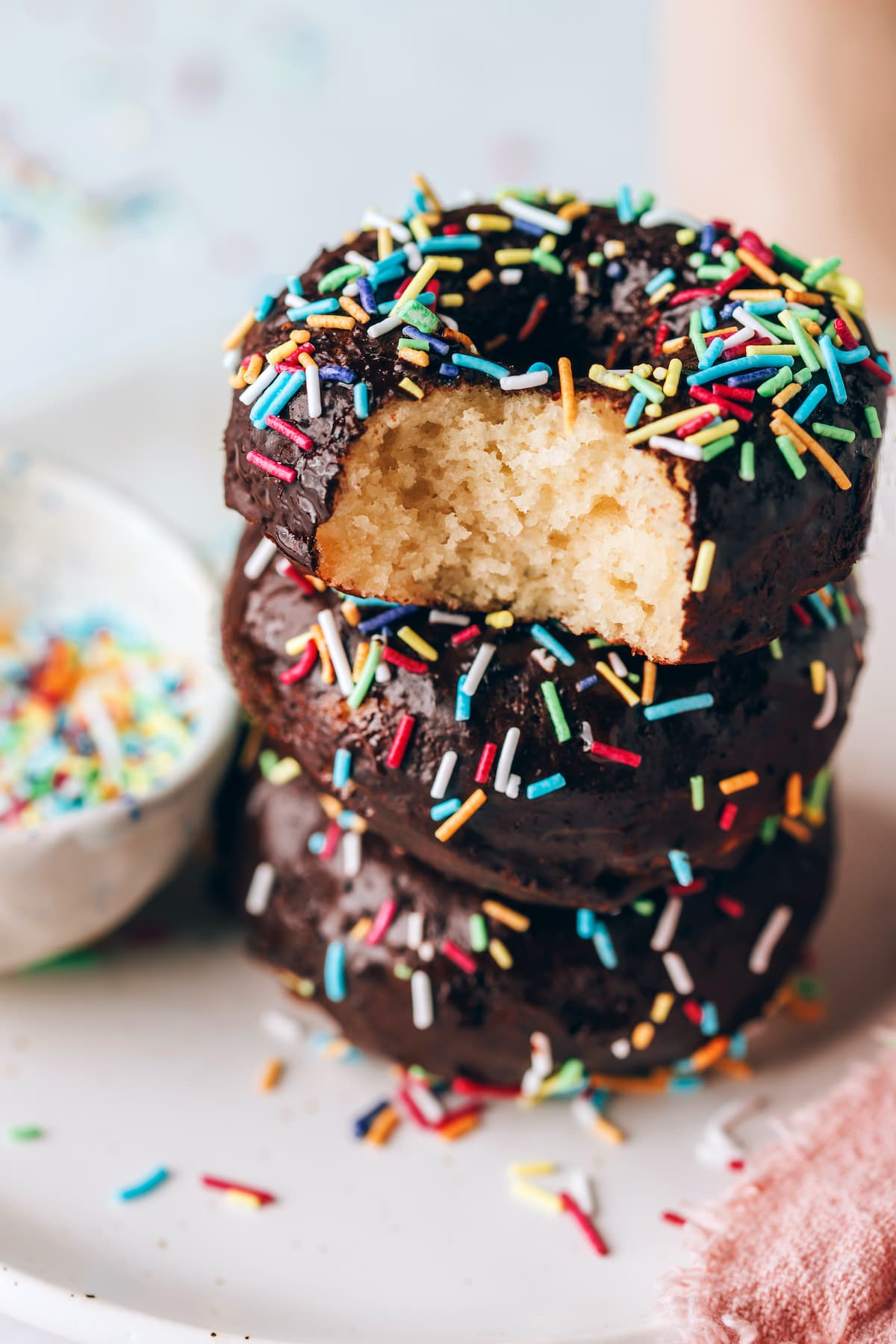 Uma pilha de donuts de proteína, o donut de cima tem uma mordida retirada.