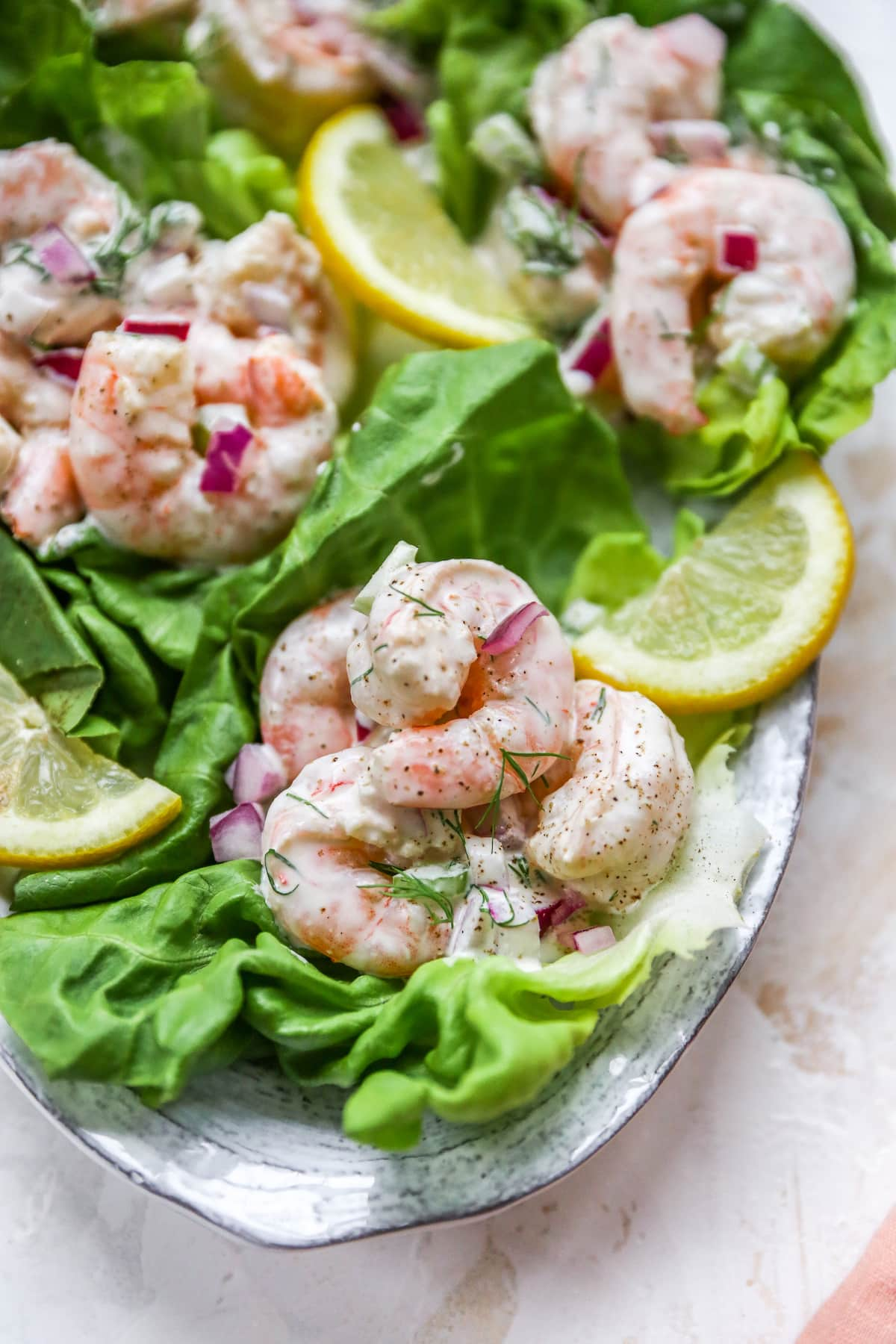 Salada de camarão servida em copos de alface. Os copos de alface estão numa travessa para servir.