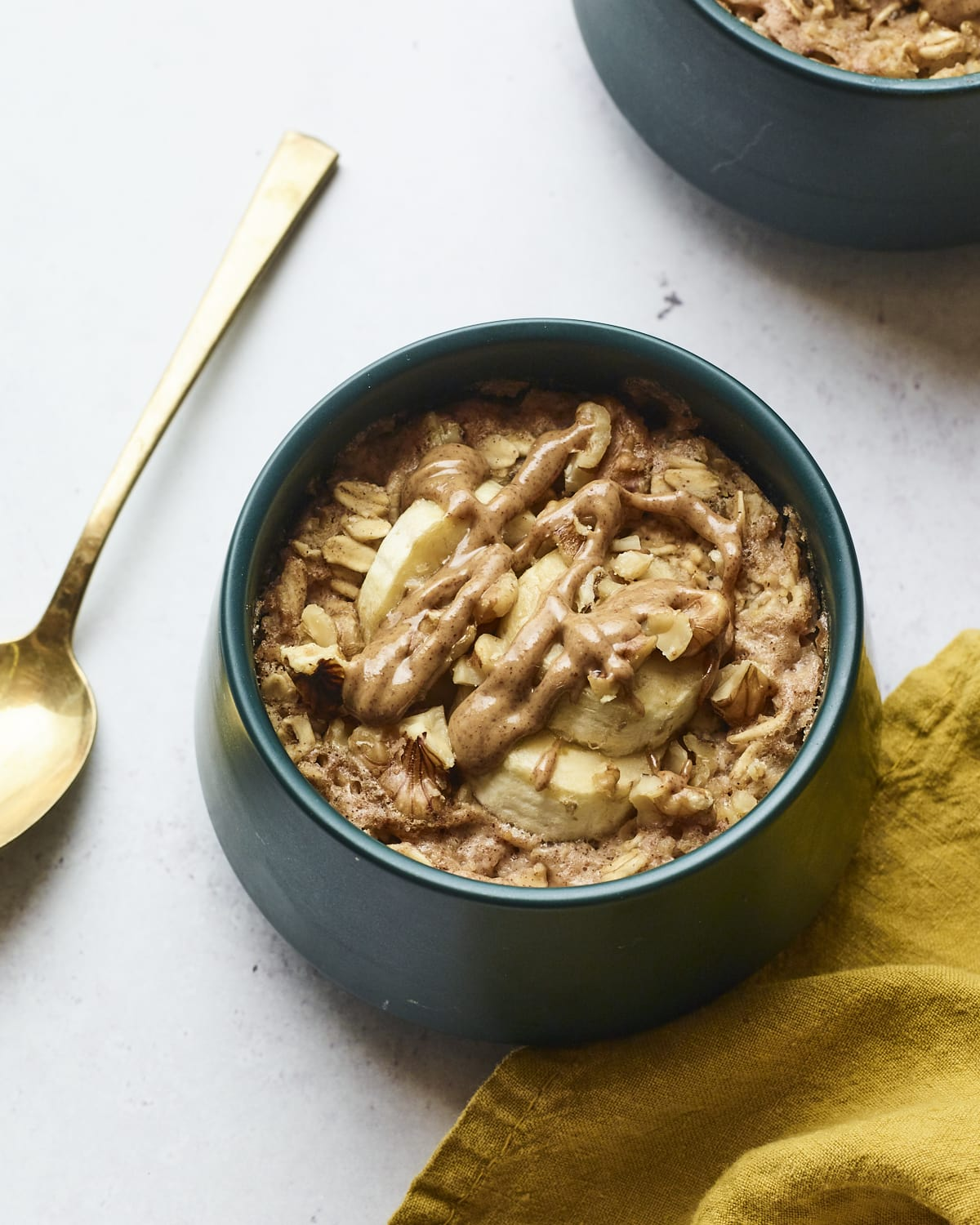 Tigela de aveia assada com banana. Uma colher e um guardanapo estão ao lado da tigela.