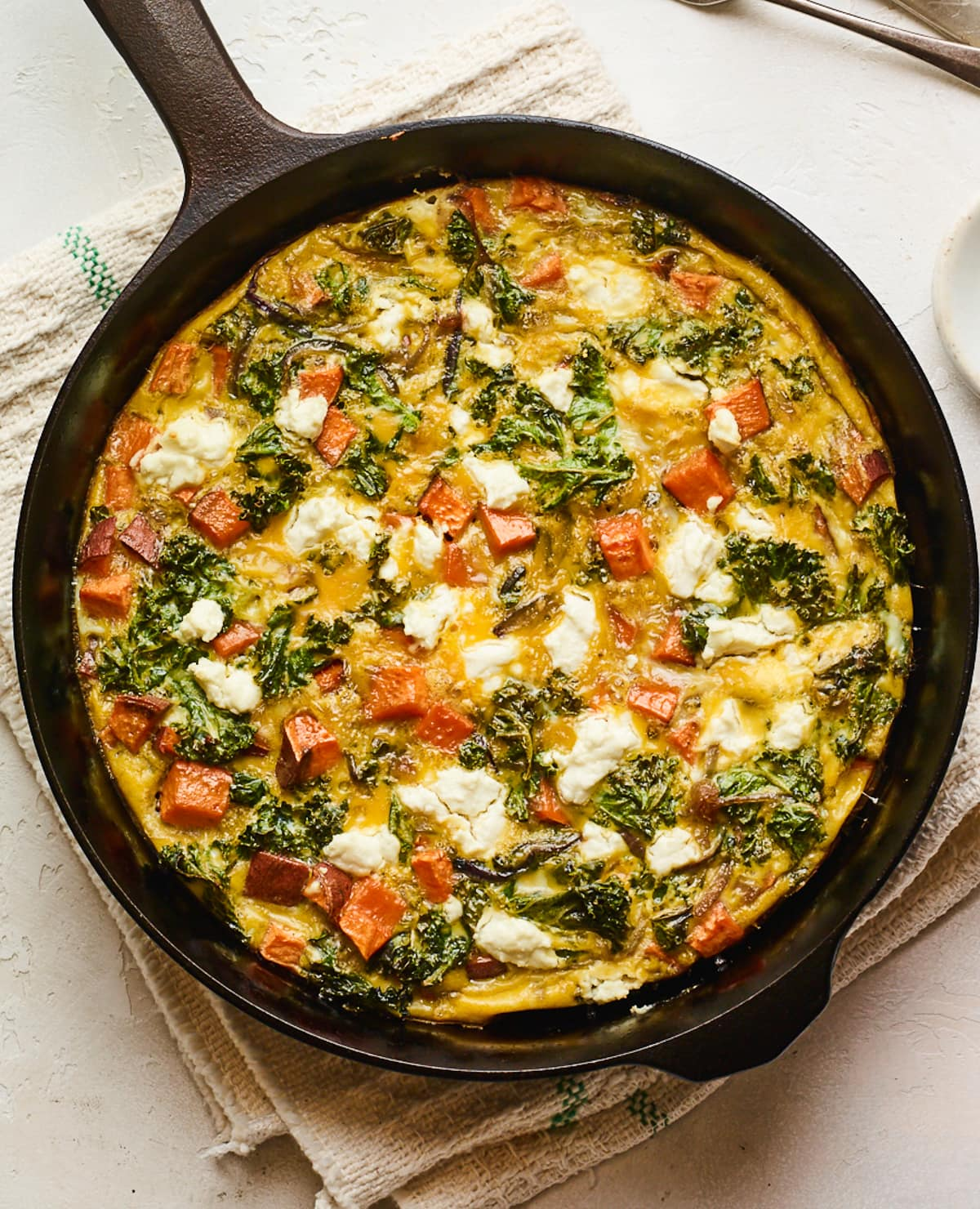 Fritata de couve de cabra com queijo de batata-doce numa frigideira.