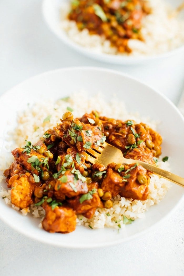 Tempeh tikka masala com grão-de-bico em arroz de couve-flor com um garfo.