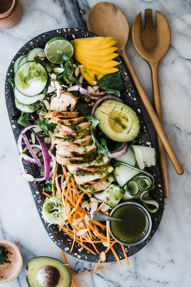 salada com abacate, manga, frango e legumes em prato preto