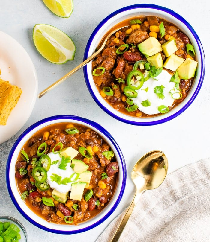 Tigelas de chili de peru servidas com abacate, creme de sopa e pão de milho.