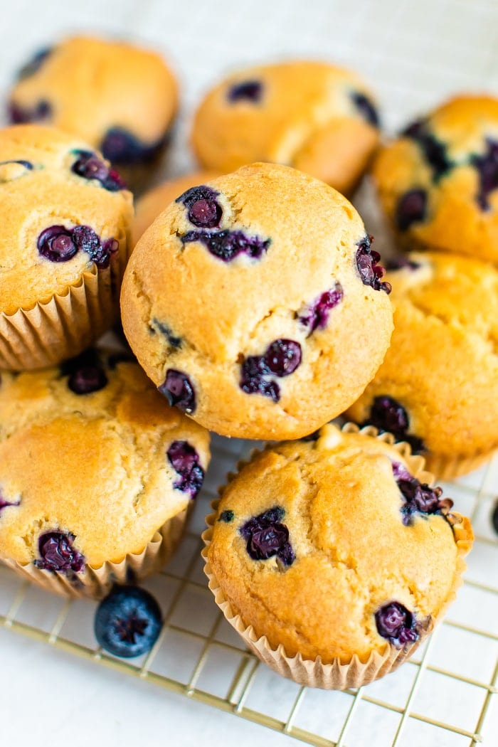 Aglomerado de muffins de mirtilo numa grelha de arrefecimento dourada.