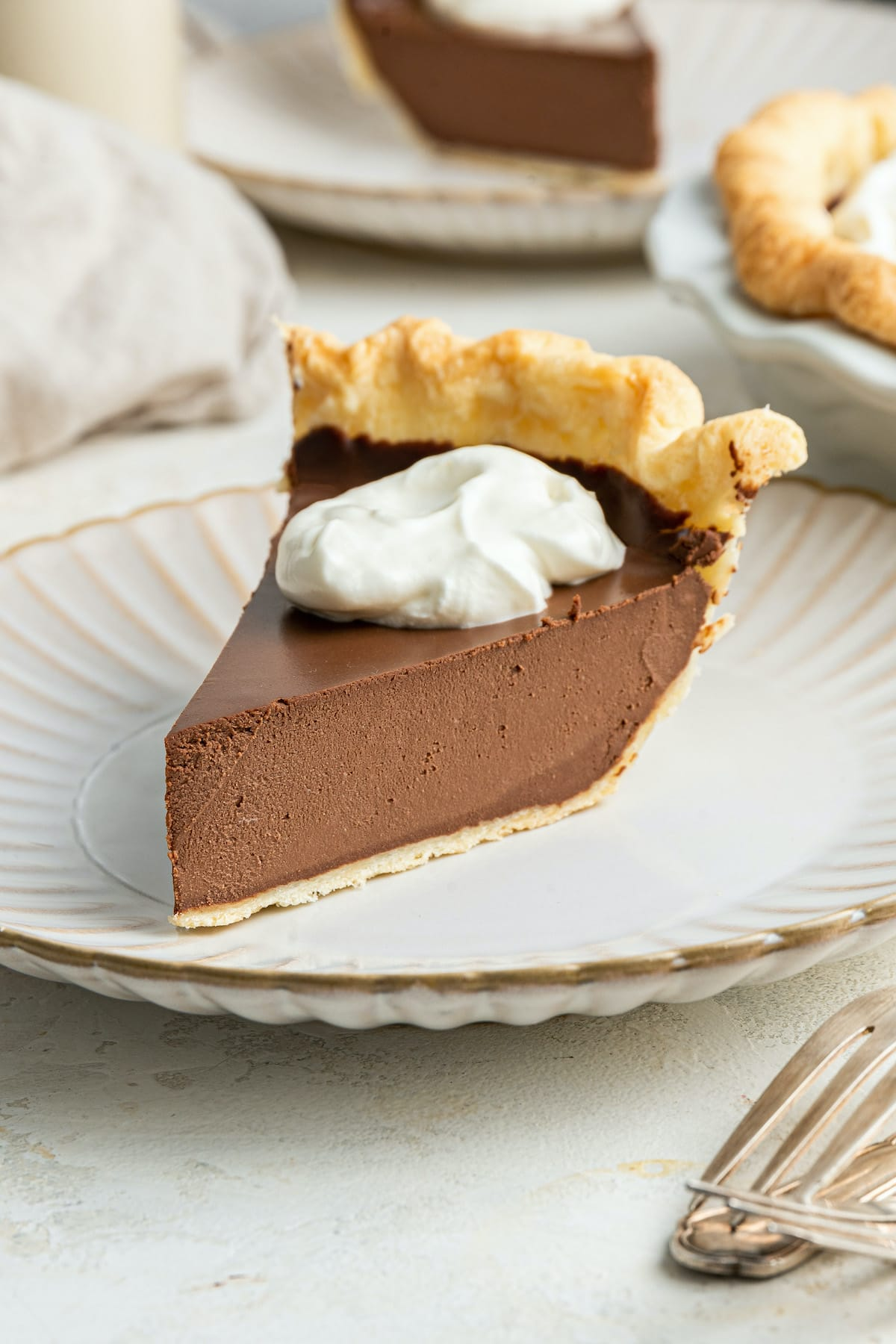 Uma fatia de torta de chocolate vegan com cobertura de chantilly em um prato.