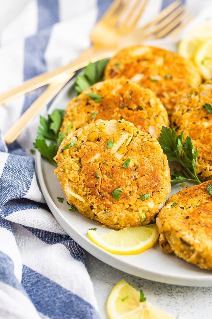 Prato com bolos de caranguejo vegan guarnecidos com salsa e rodelas de limão.