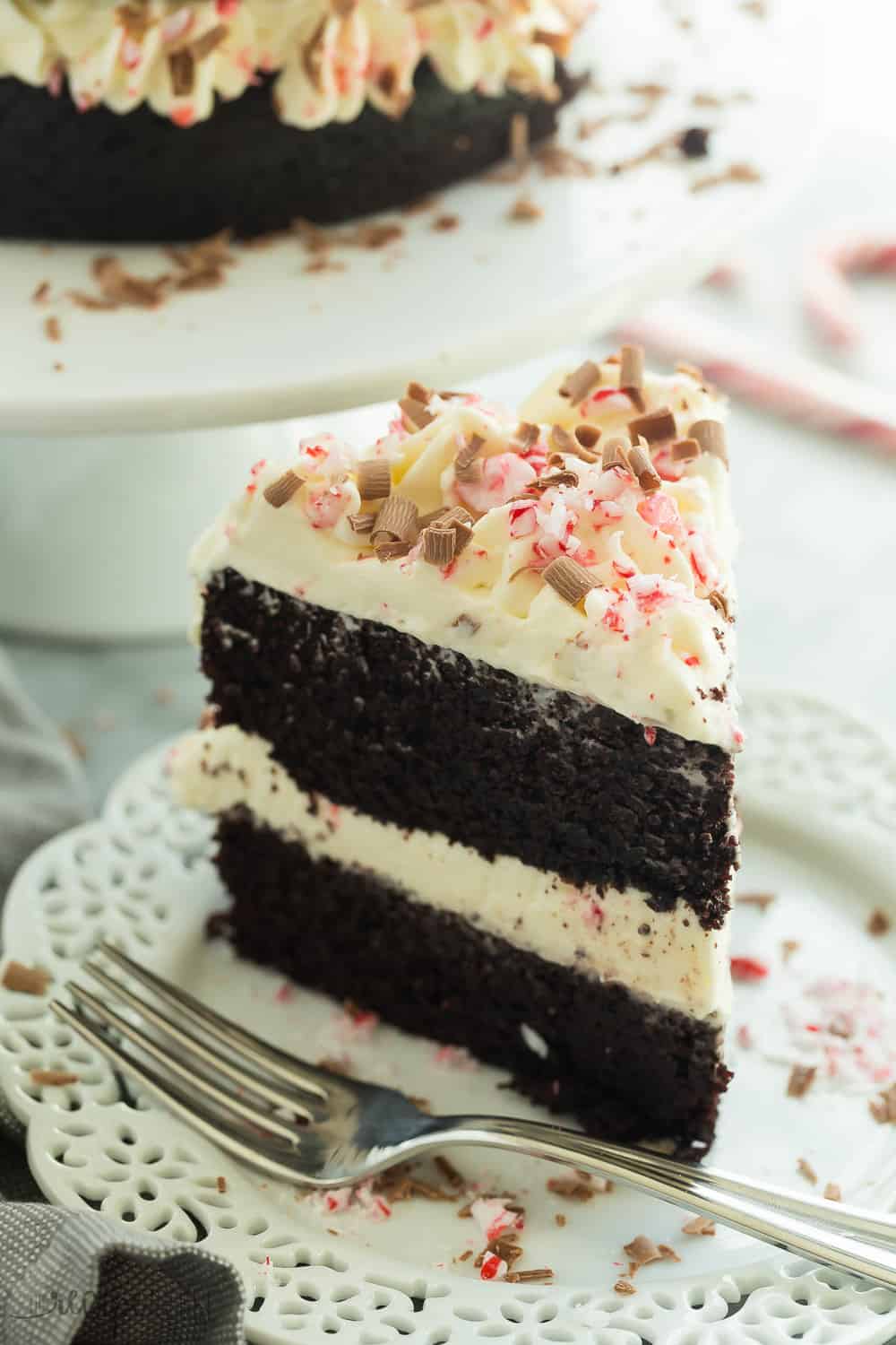 Este Double Chocolate Peppermint Cake tem duas camadas de bolo de chocolate, creme de chocolate branco batido e é acabado com bengalas de doce esmagadas e raspas de chocolate -- esta é a sobremesa que você quer levar para a festa de Natal!